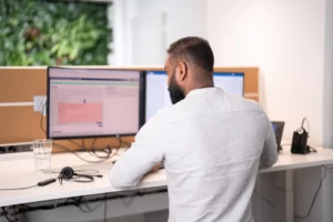 Ein Mitarbeiter arbeitet an einem PC und kümmert sich um wichtige Aufträge.