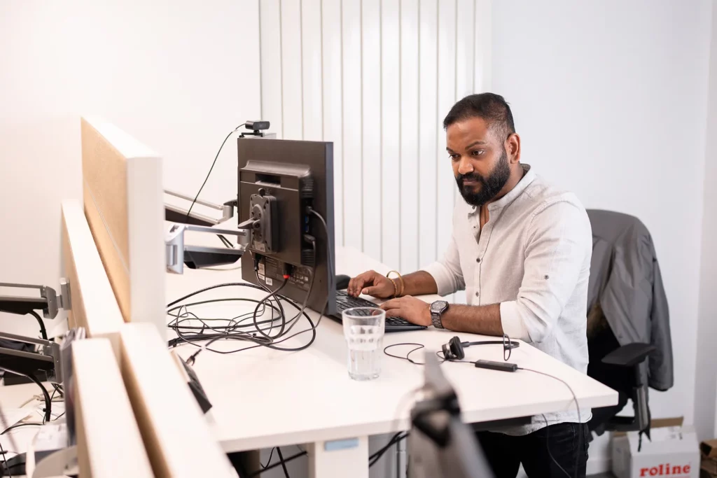 Ein Mitarbeiter von DT Netsolution arbeitet an einem PC und kümmert sich um den IT-Service.